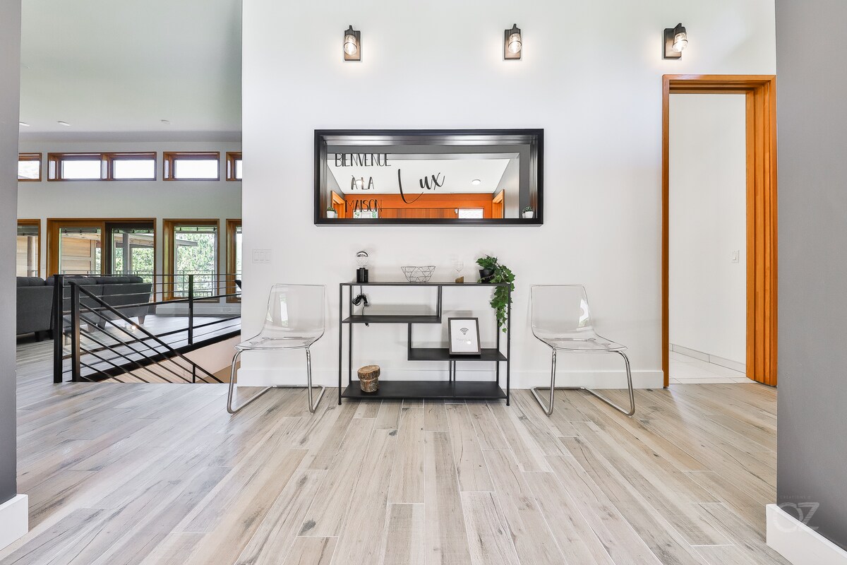 Hall d’entrée de la Maison Lux, grand miroir noir, chaises transparentes et console