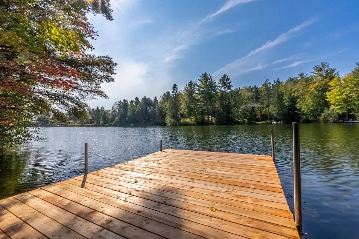 Quai de bois neuf avançant sur le lac, rive boisée et ciel dégagé