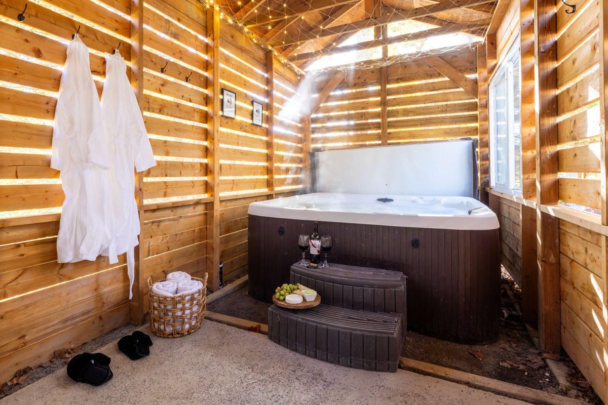 Spa abrité dans un pavillon de bois, peignoirs blancs, serviettes et guirlande lumineuse